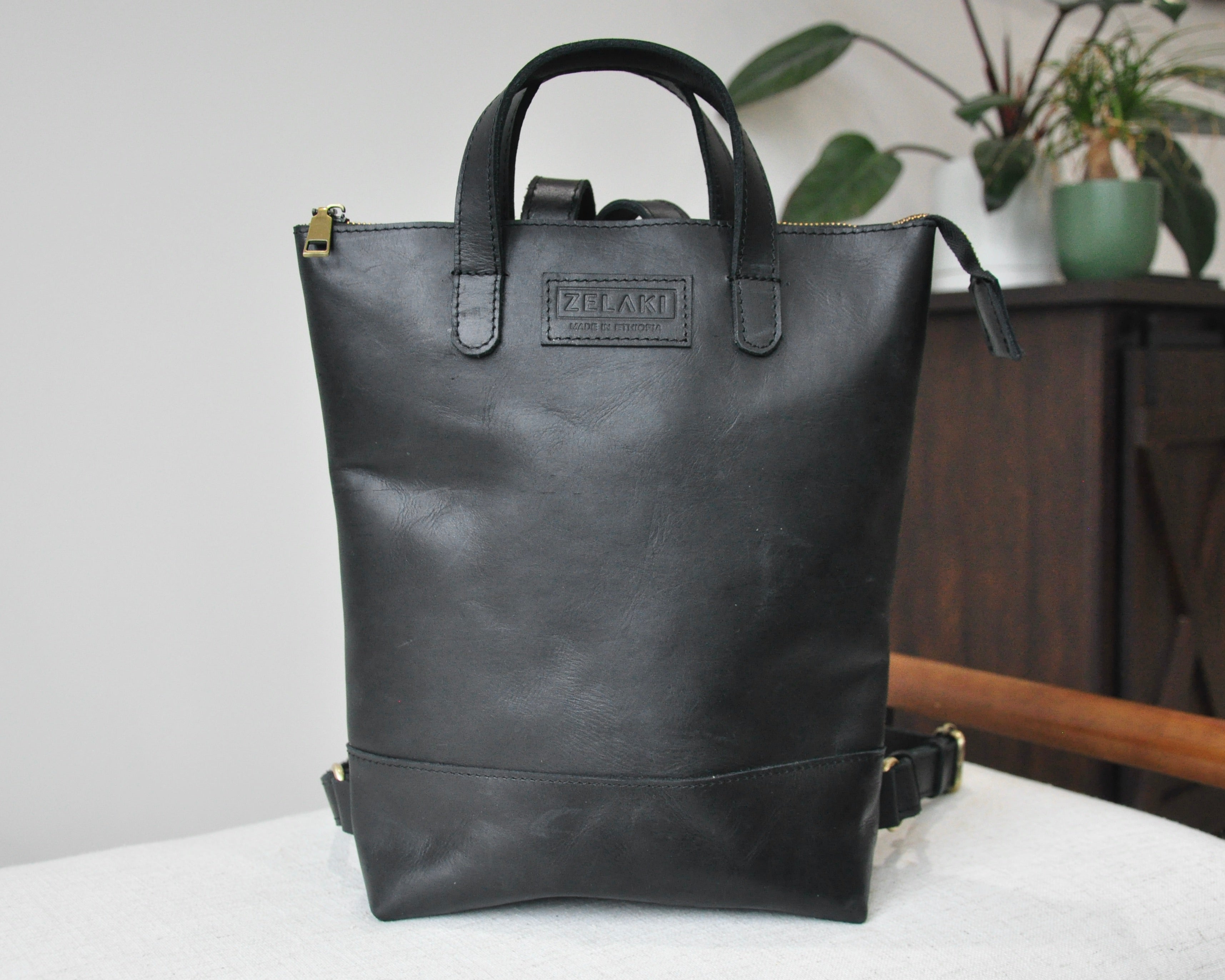 Small, black, genuine full-grain leather backpack for women with zipper, durable and handmade in Ethiopia