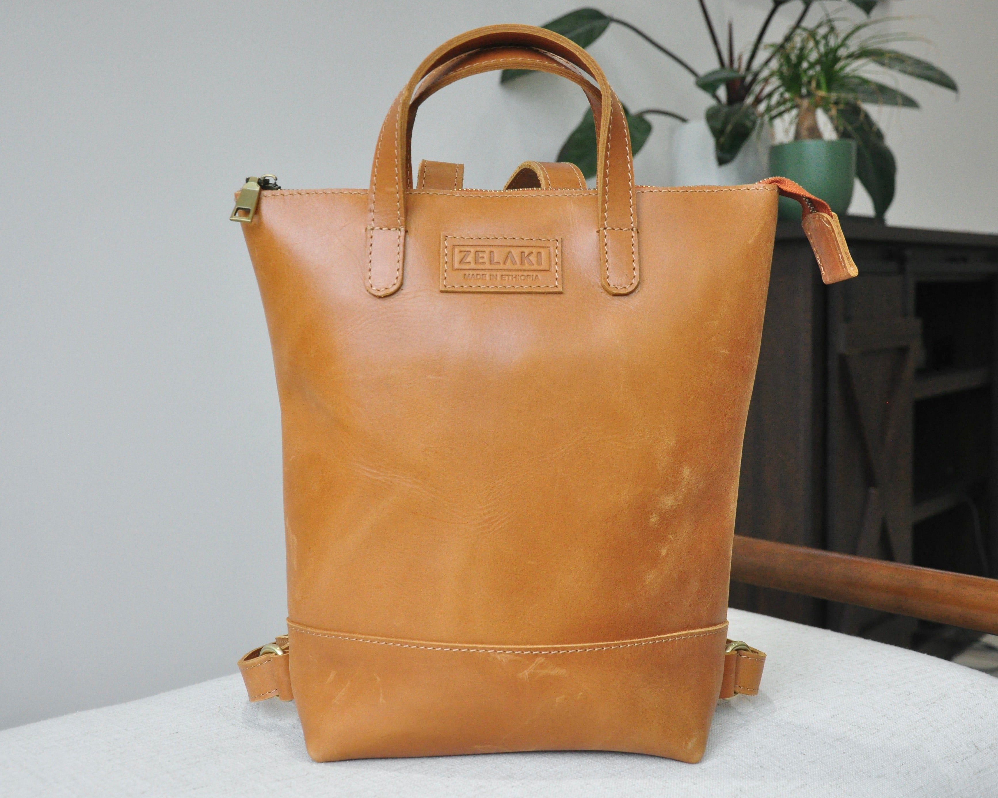 Small, tan, genuine full-grain leather backpack for women with zipper, durable and handmade in Ethiopia